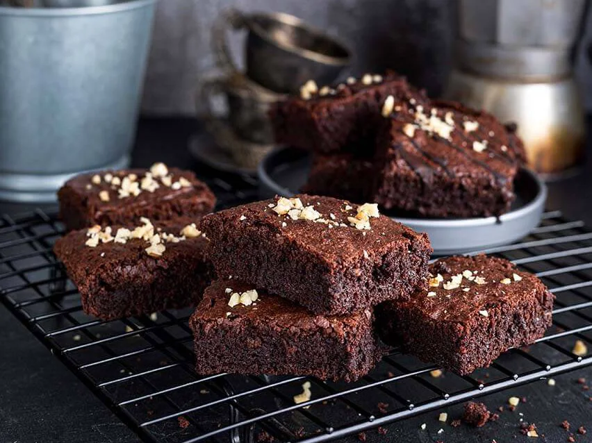 Brownies auf einem Kuchengitter, daneben eine Kanne