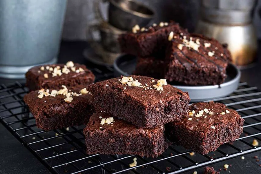 Brownies auf einem Kuchengitter, daneben eine Kanne