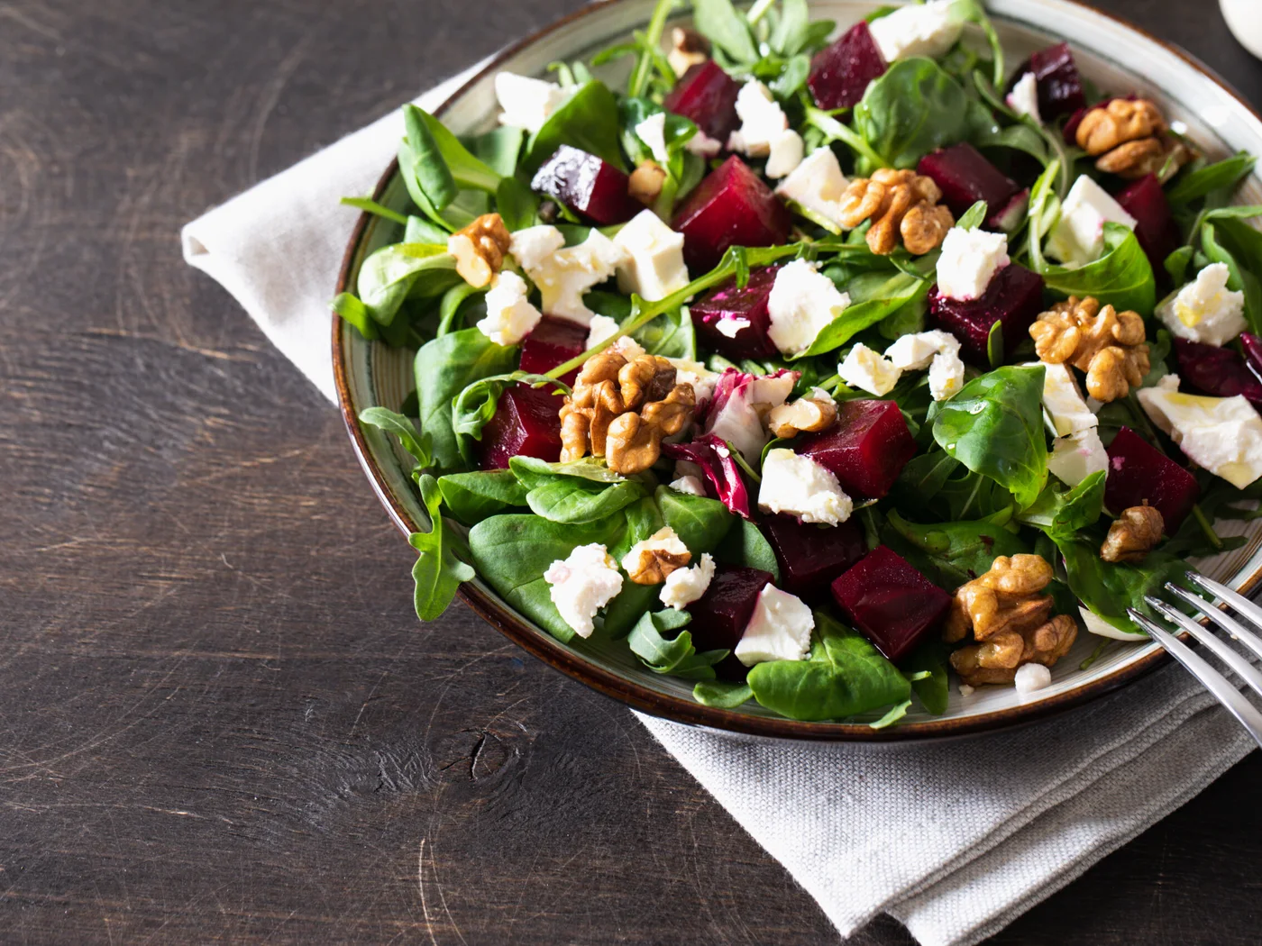 Feldsalat mit Roter Bete, Rucola, Weichkäse und Walnüssen auf einem Teller