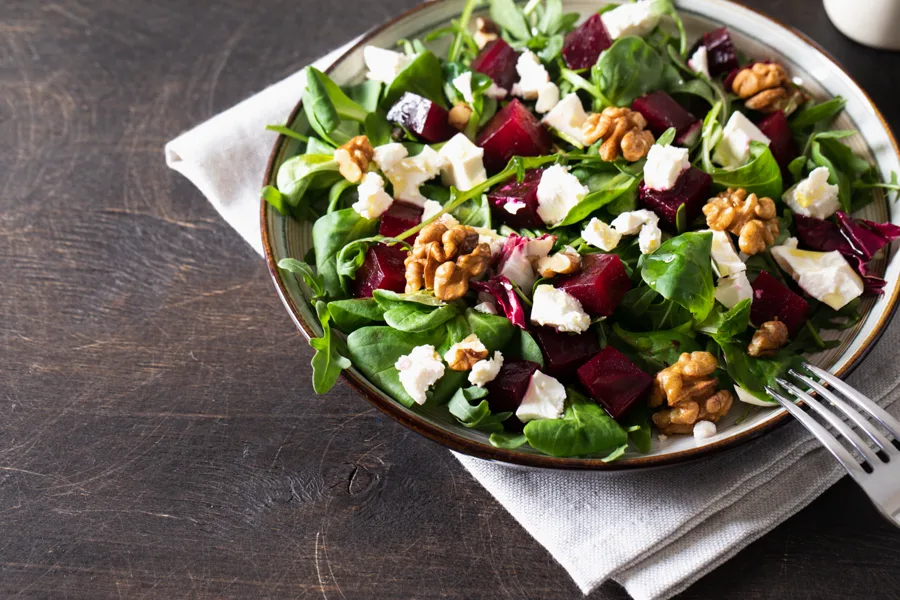 Feldsalat mit Roter Bete, Rucola, Weichkäse und Walnüssen auf einem Teller